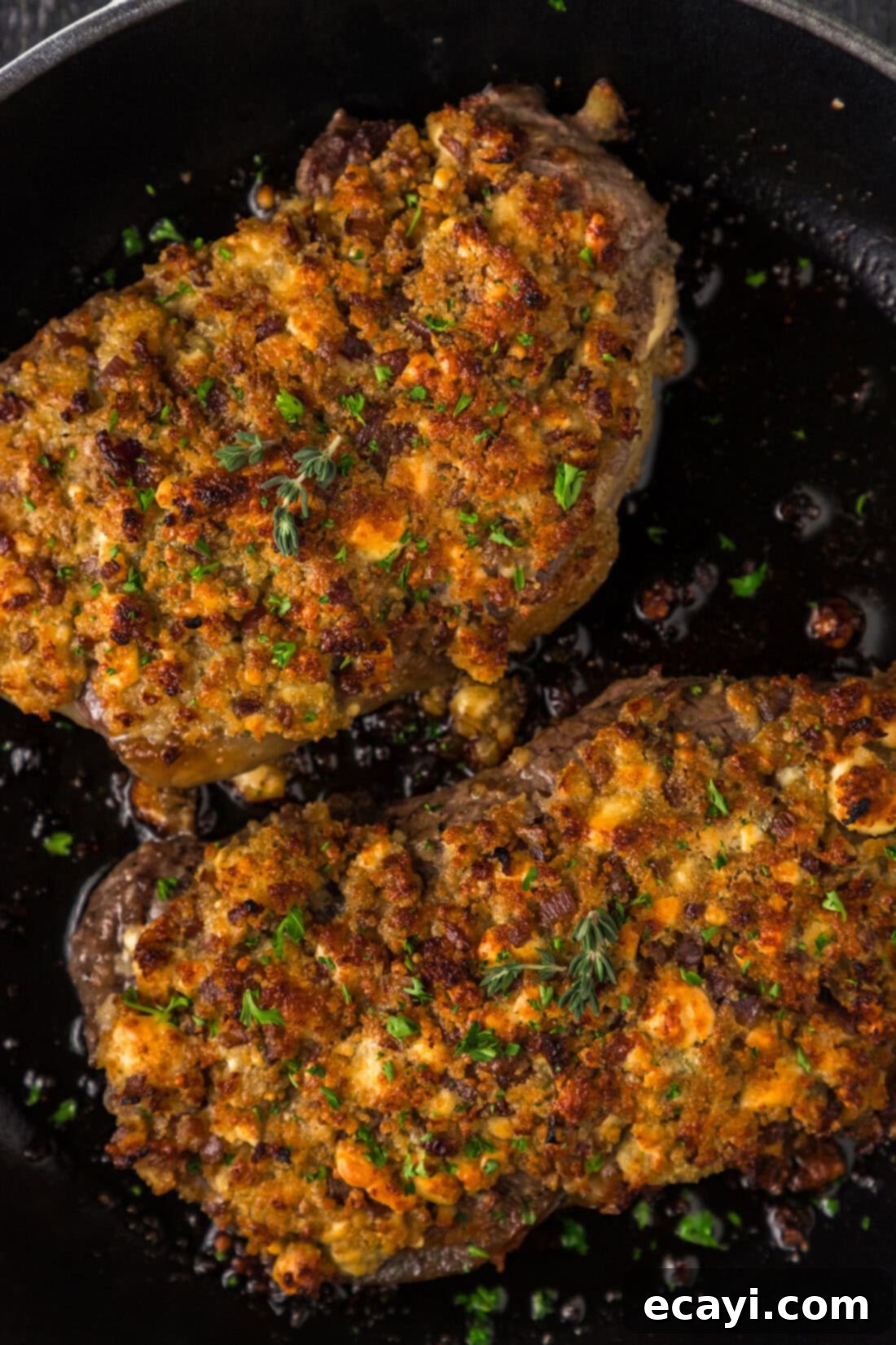Signature Blue Cheese Crusted Steak 3 Close-up photo of two perfectly seared Blue Cheese Crusted Steaks, glistening in a cast-iron skillet, ready for the oven.