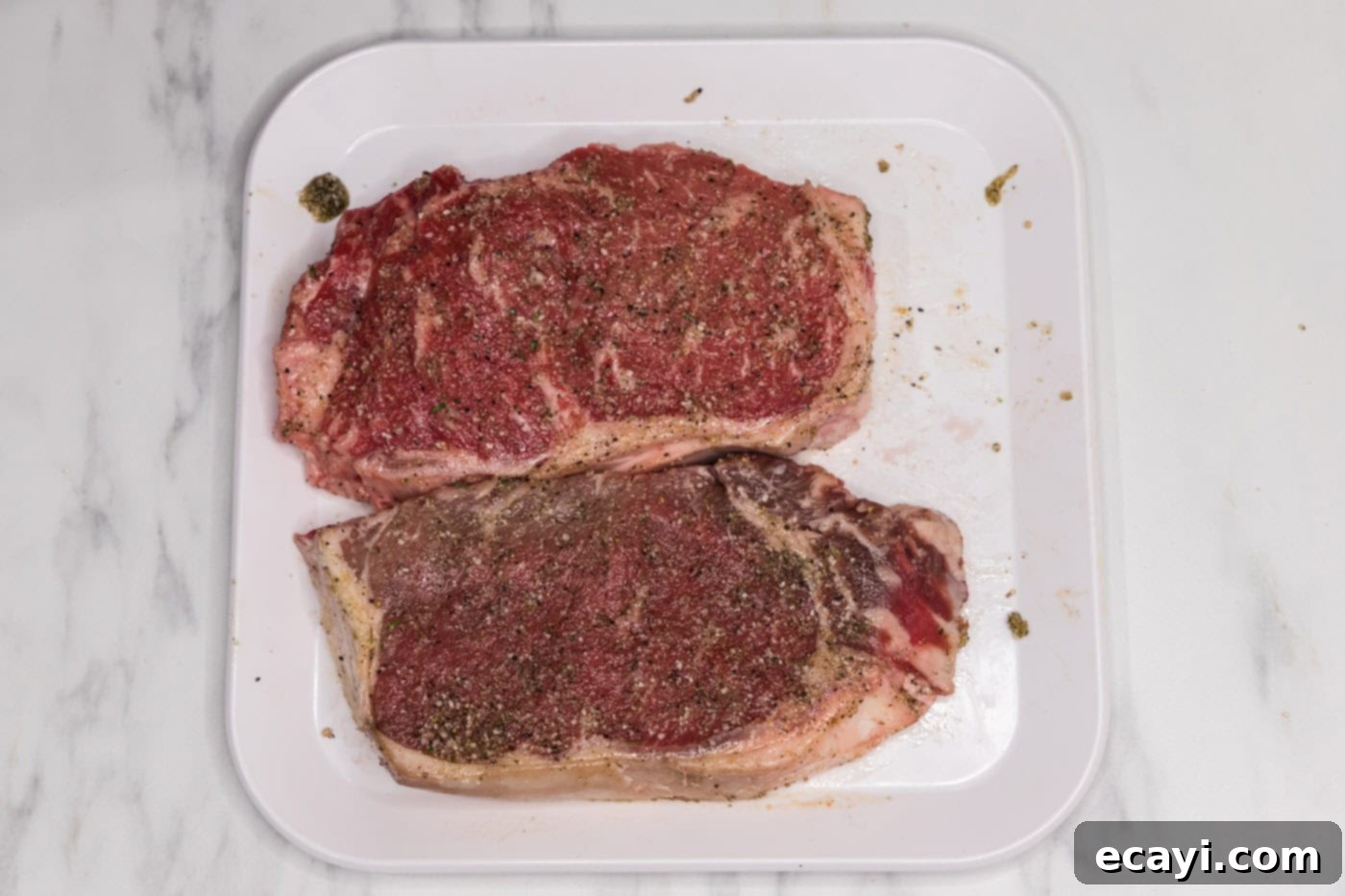 Signature Blue Cheese Crusted Steak 5 Olive oil mixture being rubbed evenly over a New York strip steak.