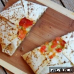 The Ultimate At-Home Crunchwrap 11 A top-down view of a delicious homemade copycat Crunchwrap Supreme, sliced in half to reveal its mouth-watering layers, presented on a rustic wooden cutting board.