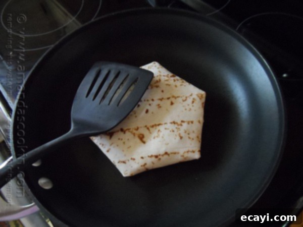 The Ultimate At-Home Crunchwrap 8 A large flour tortilla with all the fillings folded securely around the center, creating the classic Crunchwrap shape, ready for grilling.