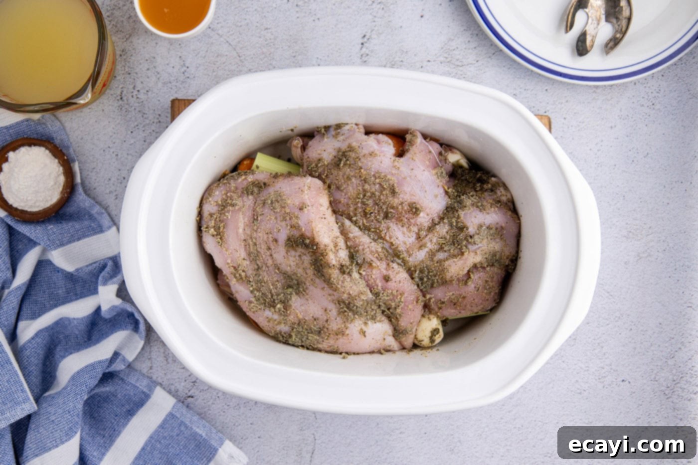 Perfectly Tender Crockpot Turkey Breast 9 Seasoned turkey breasts neatly placed over the vegetables in the slow cooker crock, ready for cooking.