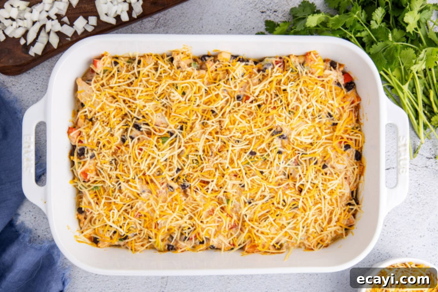 Cheesy Chicken Taco Casserole 9 shredded cheese sprinkled on top of a partially baked chicken casserole with beans and taco seasoning, before final melting.