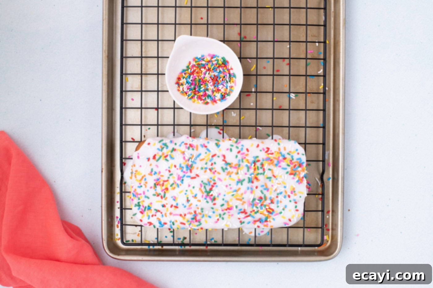 2-Ingredient Ice Cream Bread 11 A glorious loaf of ice cream bread, adorned with a sweet glaze and colorful sprinkles, cooling on a wire rack.