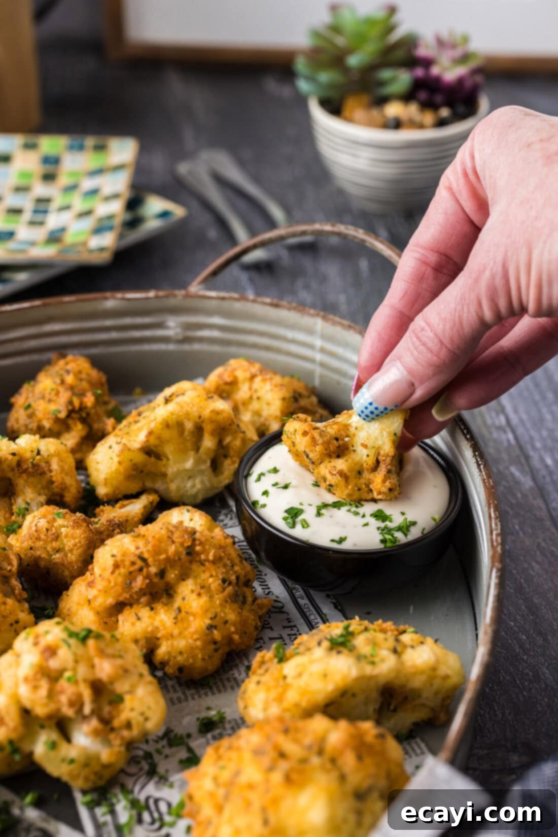 Golden Fried Florets 3 Hand dipping a golden fried cauliflower floret into a bowl of creamy ranch dressing