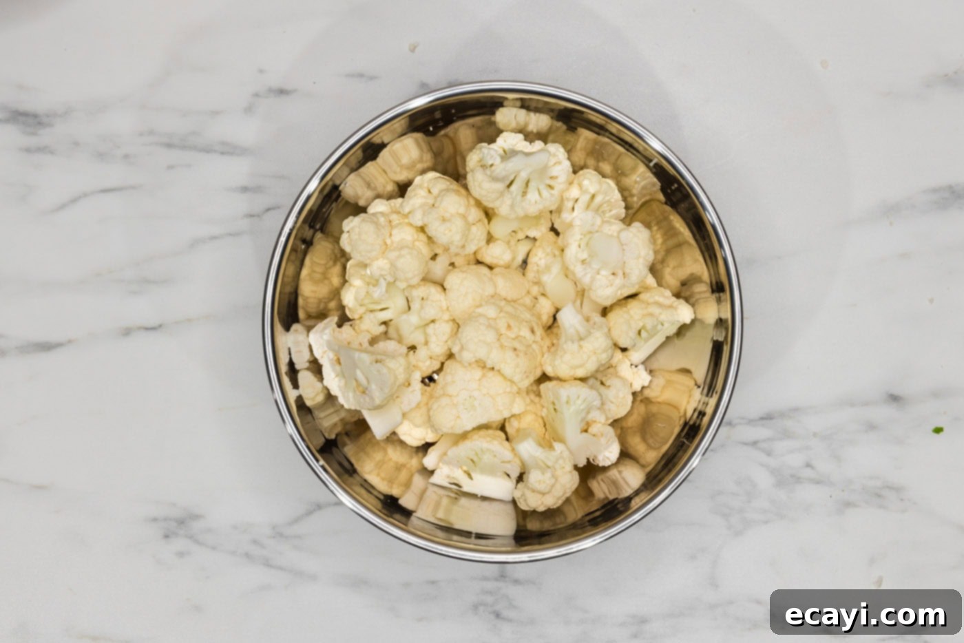 Golden Fried Florets 5 Cauliflower cut into uniform florets in a white bowl, ready for the next step in the frying process