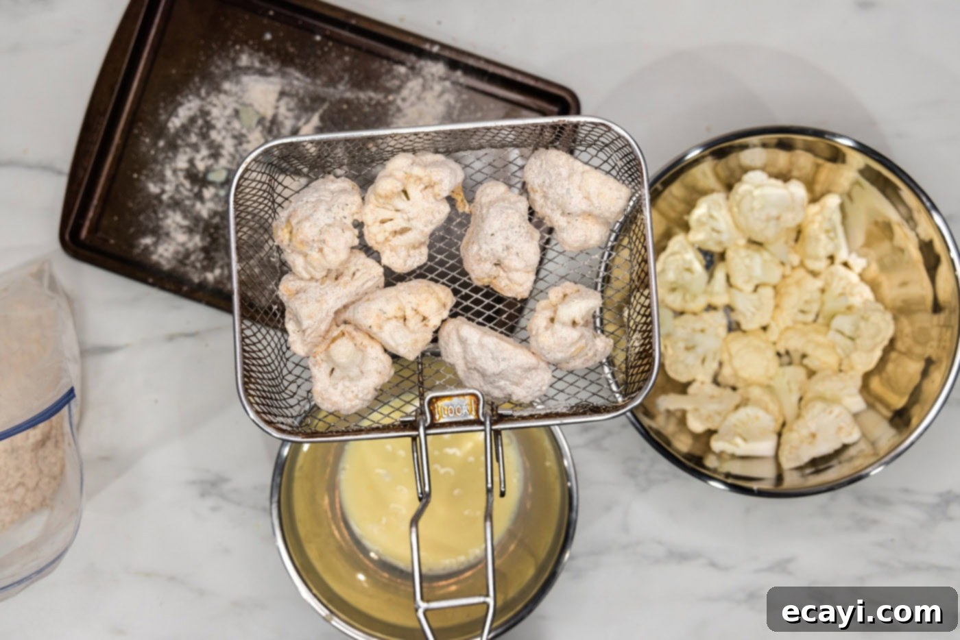 Golden Fried Florets 10 Breaded cauliflower florets neatly arranged in a deep fryer basket, prepared for frying