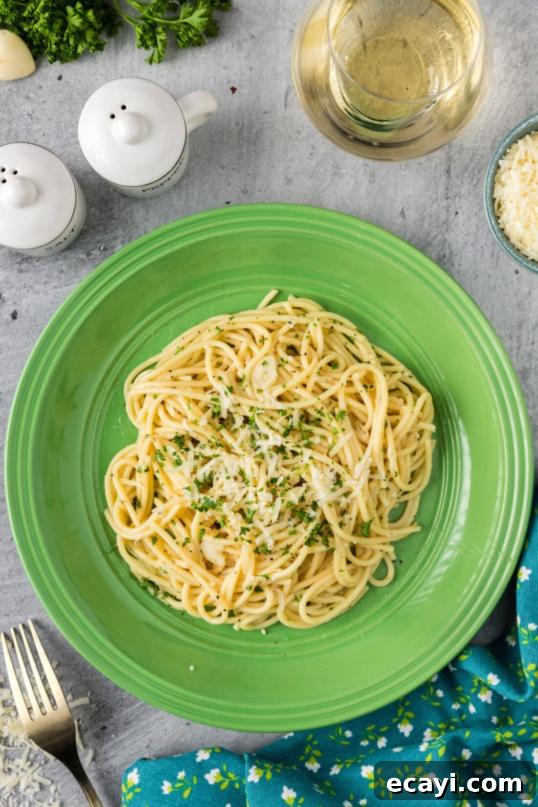 Irresistible Garlic Butter Pasta 2 A generous serving of glistening garlic butter pasta on a white plate, beautifully garnished with fresh parmesan cheese and chopped parsley, ready to be enjoyed.