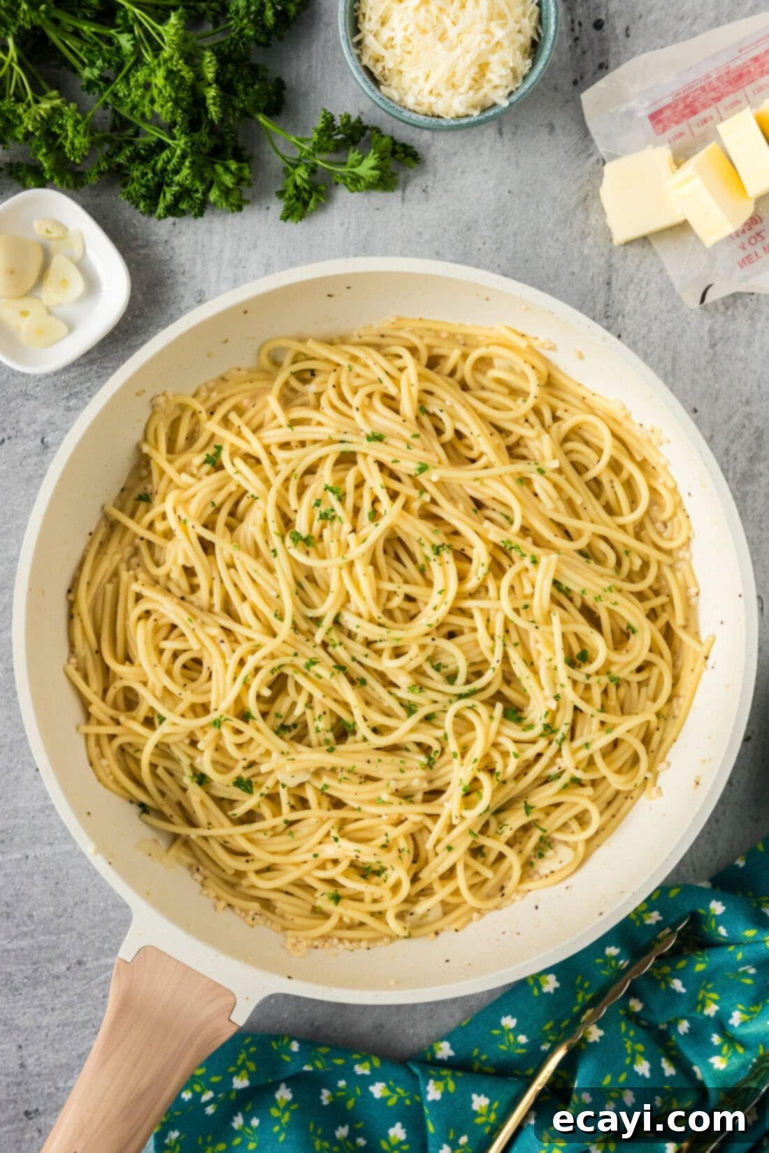 Irresistible Garlic Butter Pasta 9 A large skillet filled with freshly made garlic butter pasta, glistening with sauce and topped with herbs, on a wooden surface.