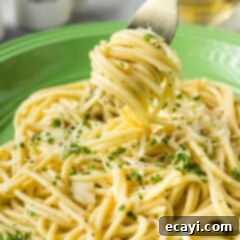 Irresistible Garlic Butter Pasta 10 Garlic Butter Pasta twirled around a fork, held above a plate with more pasta, ready for a bite.