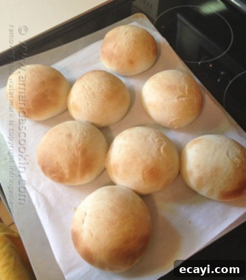 Soft and Fluffy Homemade Burger Buns 9 Golden brown homemade hamburger buns fresh out of the oven, steam gently rising.