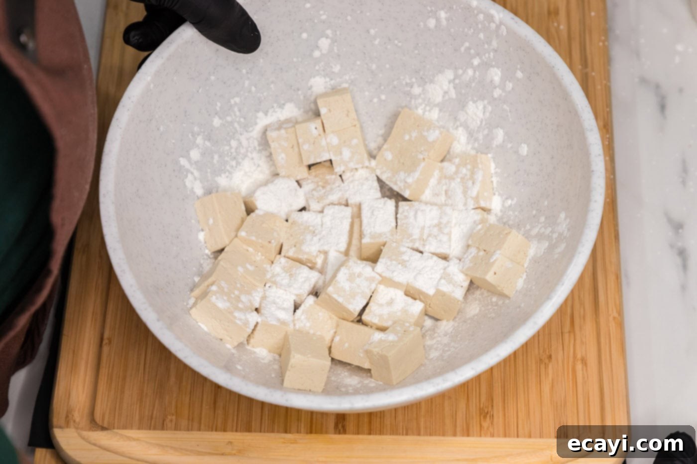 Fiery Tofu 6 cubed tofu with cornstarch on top in a bowl, ready to be coated
