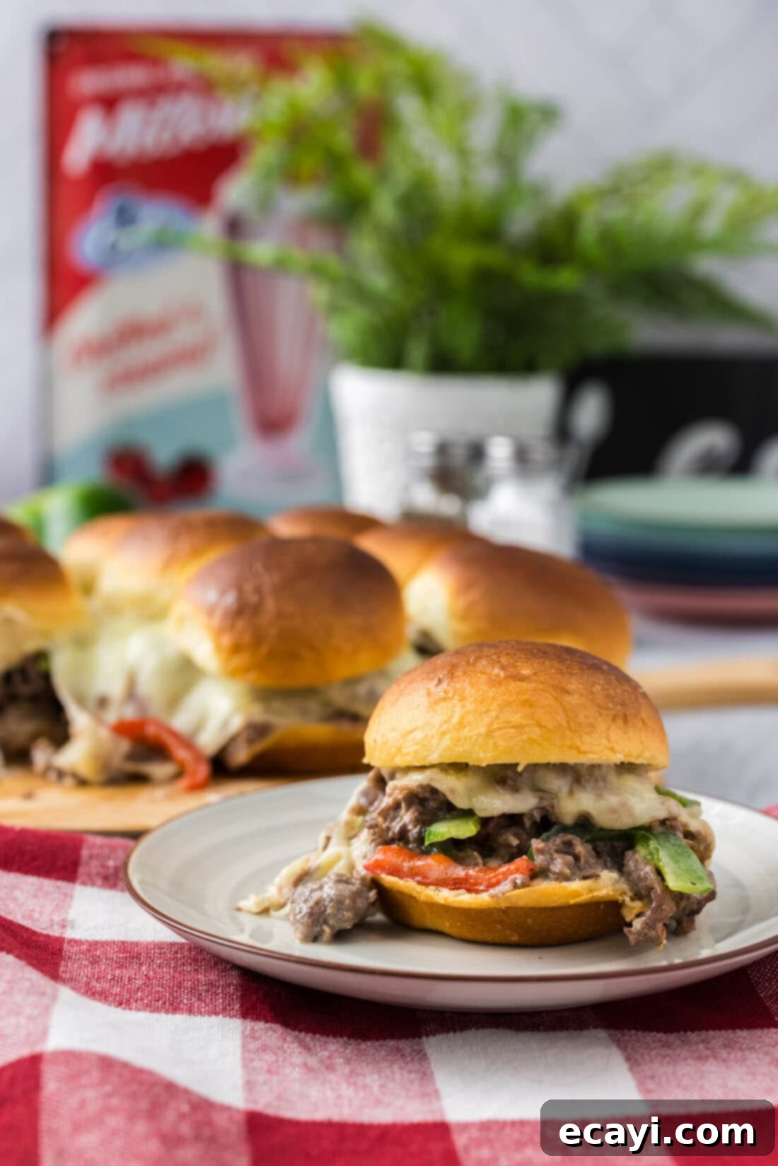 Cheesesteak Slider Bites 13 Philly Cheesesteak Slider on a plate with more Philly Cheesesteak Sliders in the background