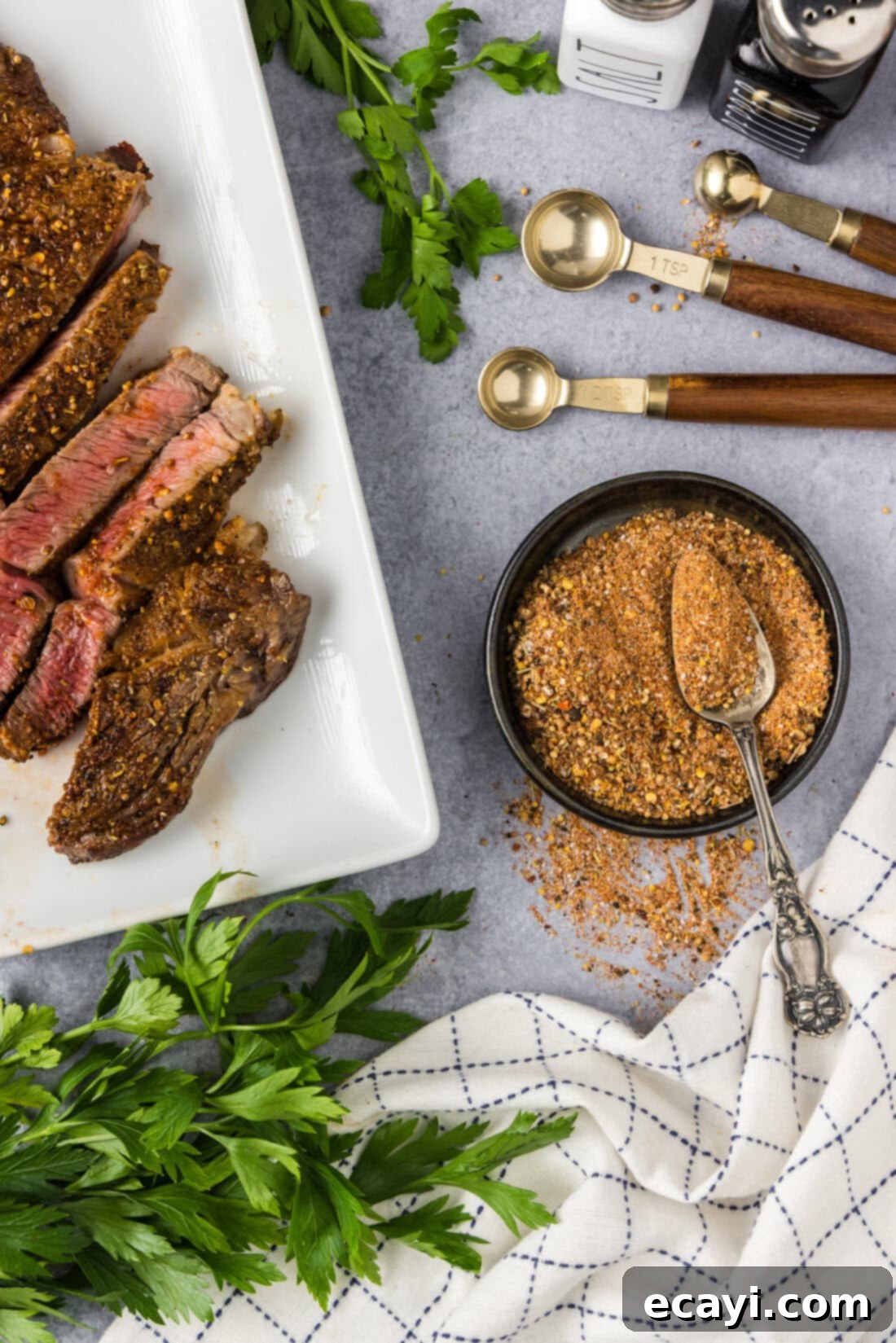 Crafting Your Own Montreal Steakhouse Blend 2 Bowl of Homemade Montreal Steak Seasoning with a spoon in it and cooked steak to the side, ready to be enjoyed.