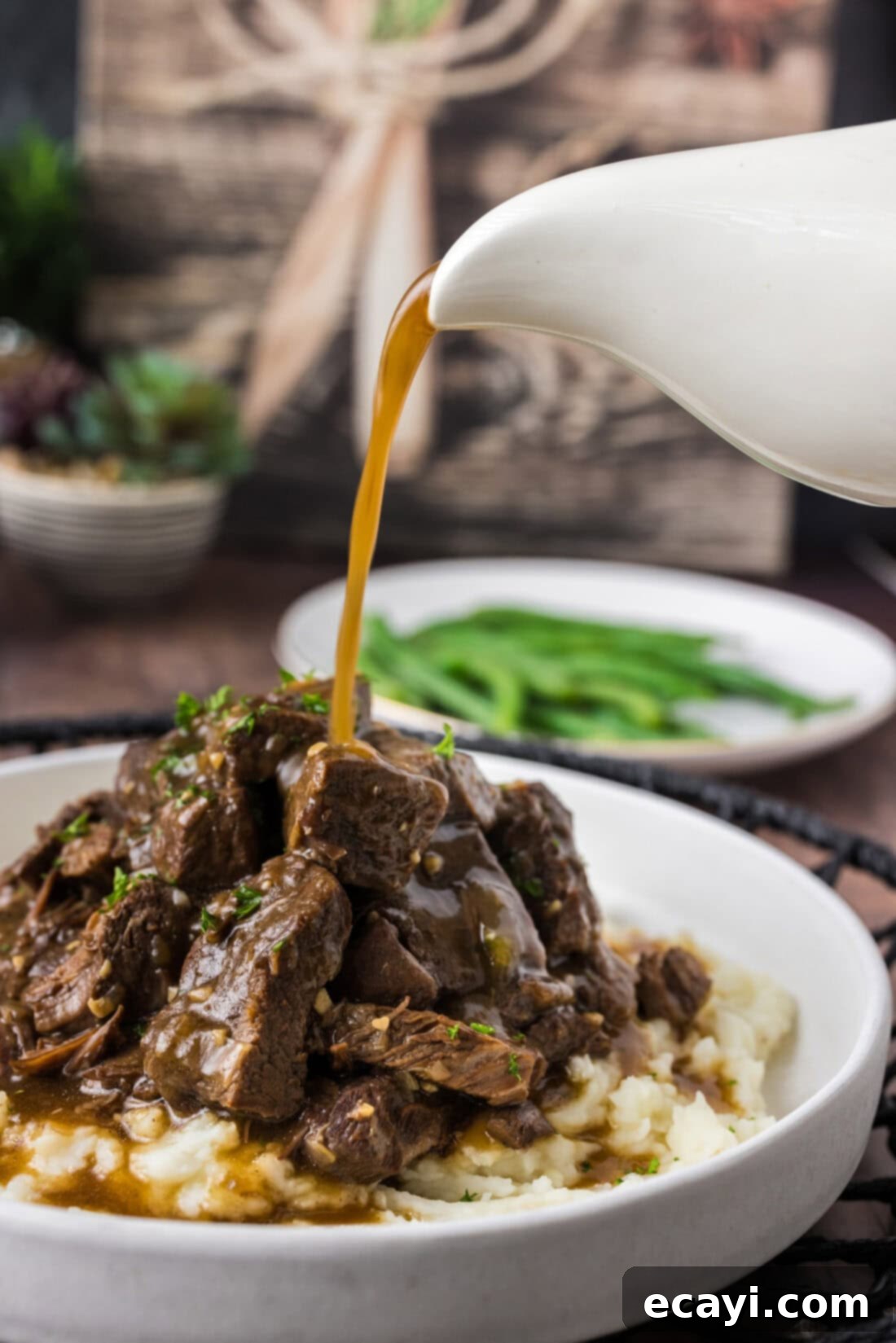 Easy Instant Pot Beef Tips and Gravy 3 Gravy being poured over a pile of Instant Pot Beef Tips and mashed potatoes