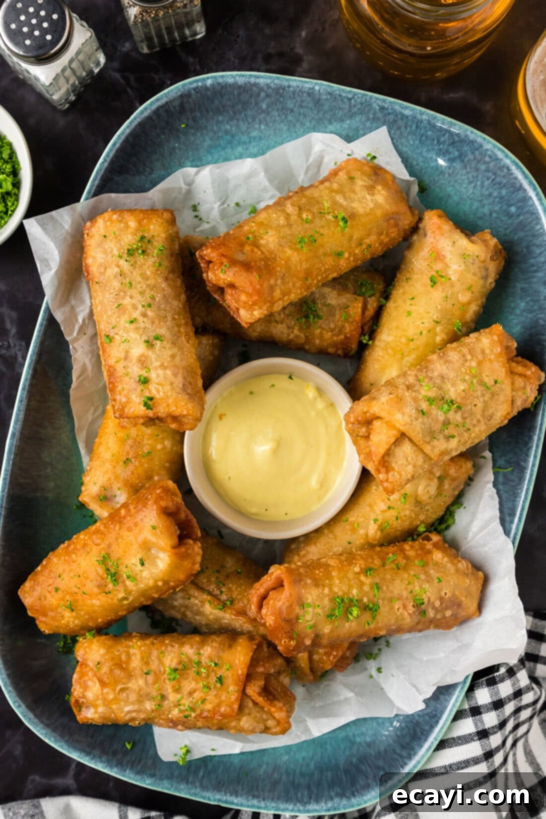 Crispy Corned Beef Egg Rolls 2 Corned Beef Egg Rolls on a blue platter with a bowl of dipping sauce in the middle