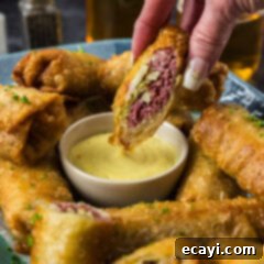 Crispy Corned Beef Egg Rolls 15 Half a Corned Beef Egg Roll held above a bowl of dipping sauce