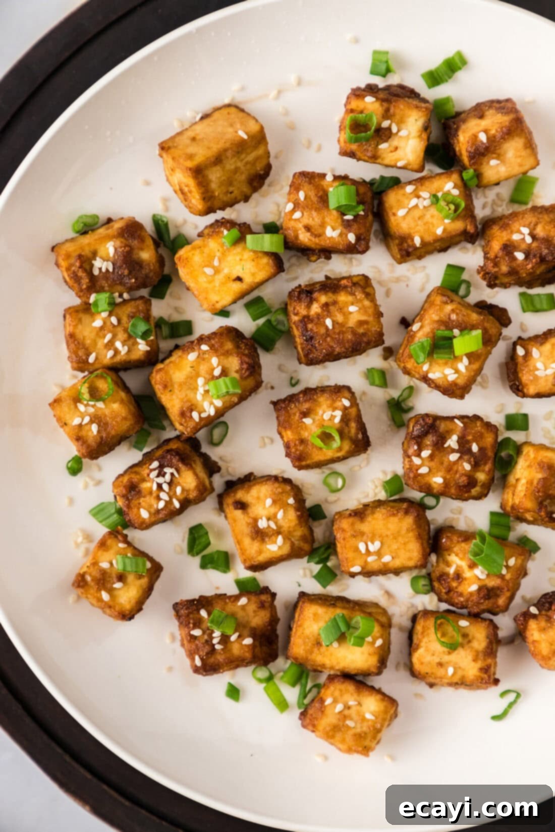 Crispy Air Fryer Tofu 2 Close up photo of a plate of perfectly golden and crispy Air Fryer Tofu, garnished with sesame seeds and green onions