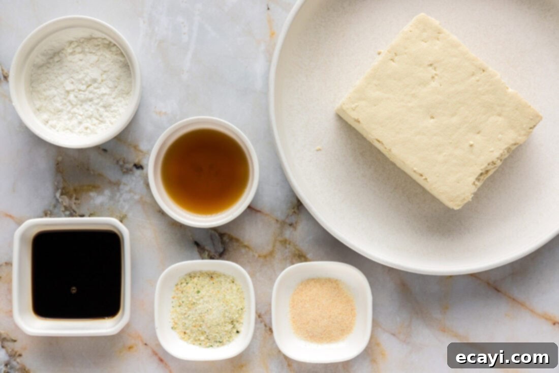 Crispy Air Fryer Tofu 4 All the ingredients laid out for Air Fryer Tofu: a block of tofu, cornstarch, onion powder, garlic salt, soy sauce, and sesame oil