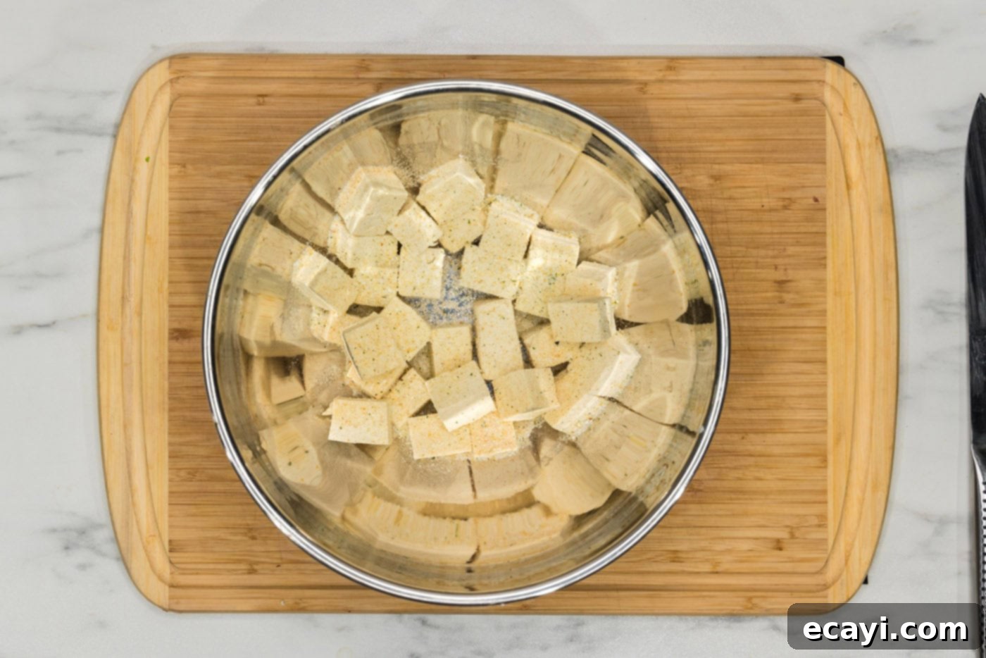 Crispy Air Fryer Tofu 6 cubed tofu in a bowl with seasonings like onion powder and garlic salt