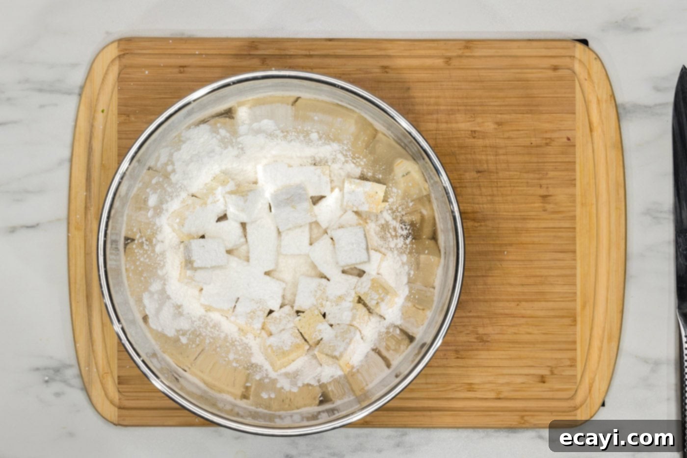 Crispy Air Fryer Tofu 7 cornstarch being added to a bowl of seasoned tofu cubes