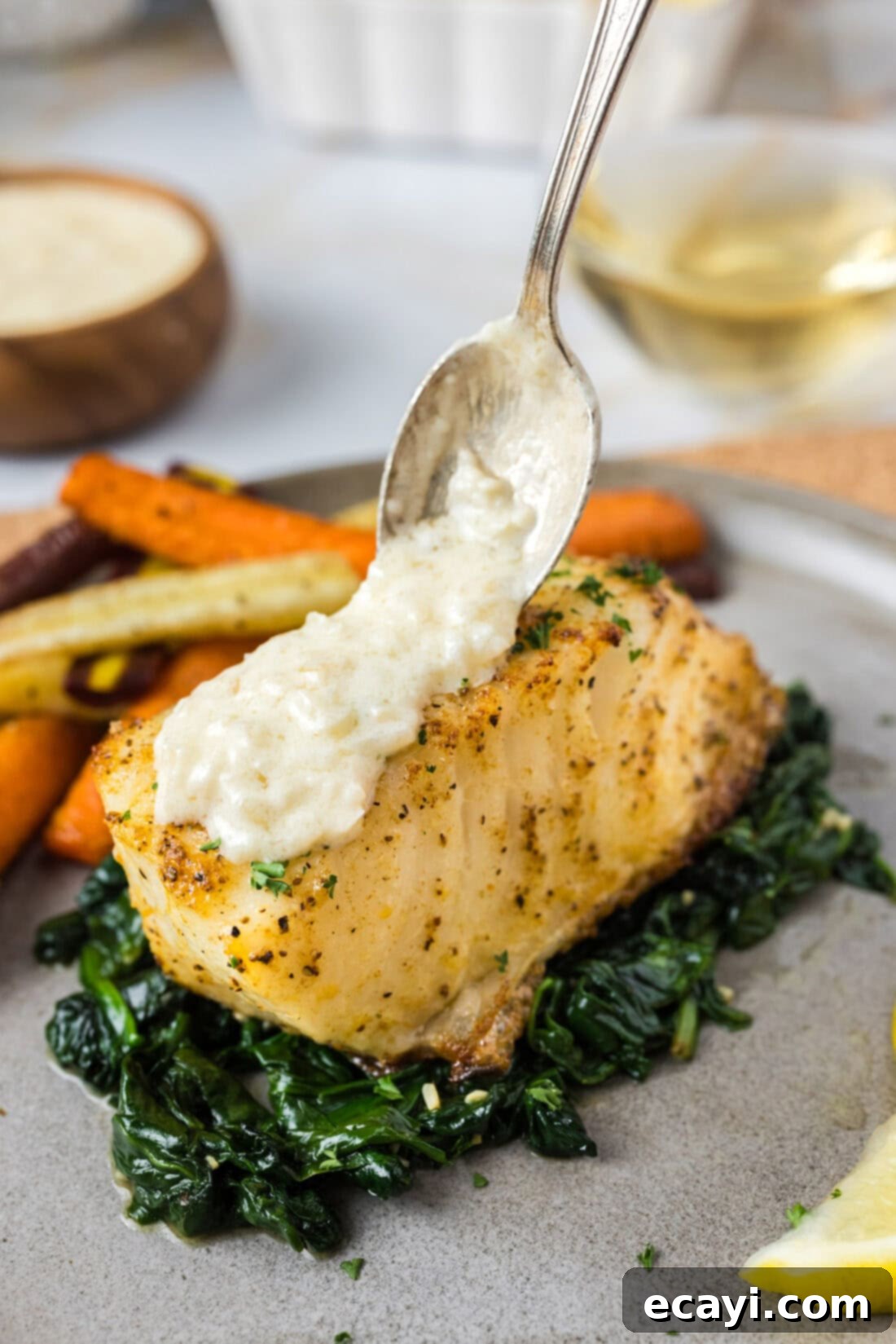 Perfectly Baked Chilean Sea Bass 36 Beurre Blanc Sauce being spooned over perfectly baked Chilean Sea Bass fillets, showcasing a gourmet meal ready to be enjoyed.