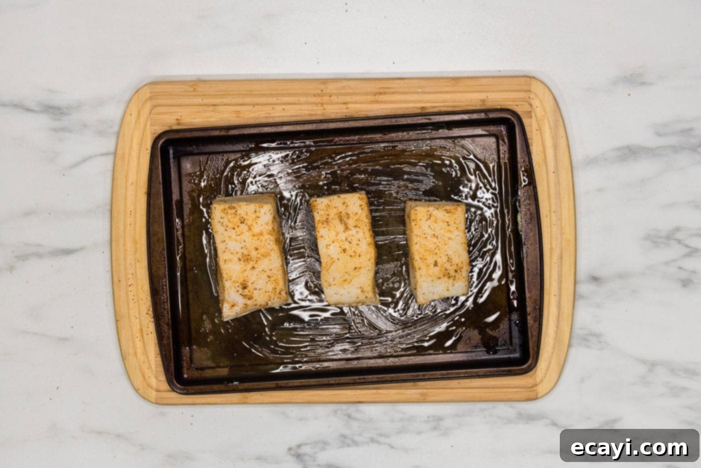 Perfectly Baked Chilean Sea Bass 6 Seasoned Chilean sea bass fillets neatly arranged on a baking sheet, ready for the oven.