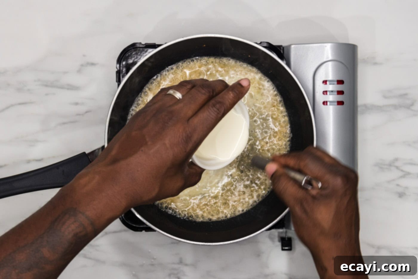 Perfectly Baked Chilean Sea Bass 9 Whisking heavy whipping cream into the simmering sauce in a skillet, ensuring a smooth and rich consistency.