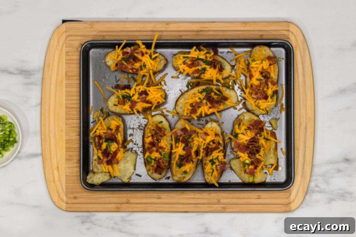 Loaded Potato Boats 10 bacon, shredded cheese, chives, and green onions on potato skins on a baking sheet