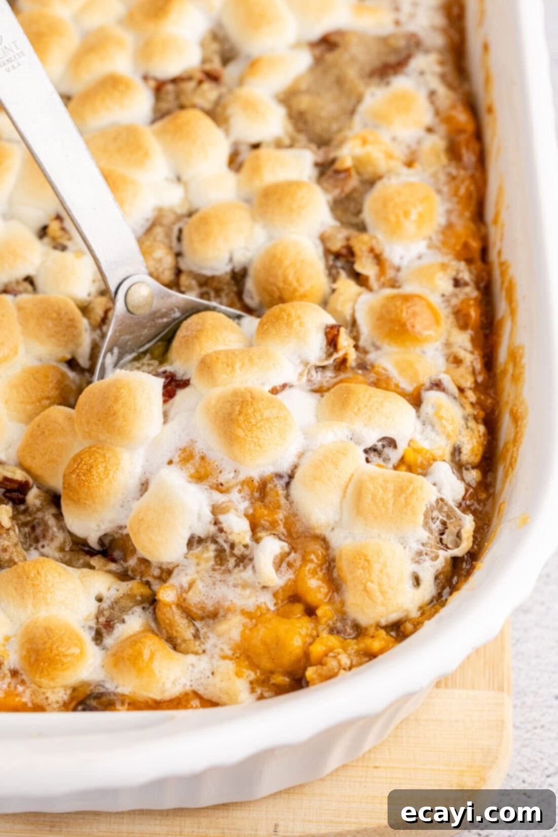 Golden Sweet Potato Bliss 2 Close up photo of a spoon in Sweet Potato Casserole, showcasing the creamy texture, golden marshmallows, and crunchy pecan streusel.