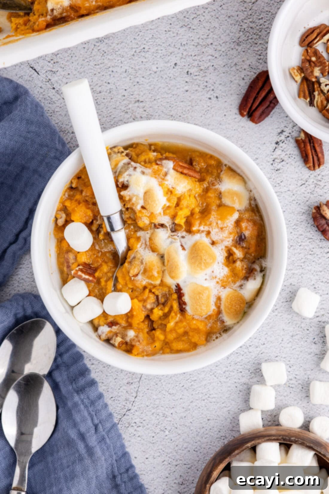 Golden Sweet Potato Bliss 5 A bowl of freshly baked Sweet Potato Casserole, garnished with extra pecans and golden marshmallows, ready to be served as a holiday side dish.