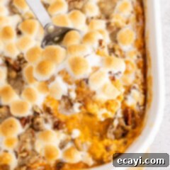 Golden Sweet Potato Bliss 6 Close up photo of a spoonful of Sweet Potato Casserole in the casserole dish with golden marshmallows and pecans.