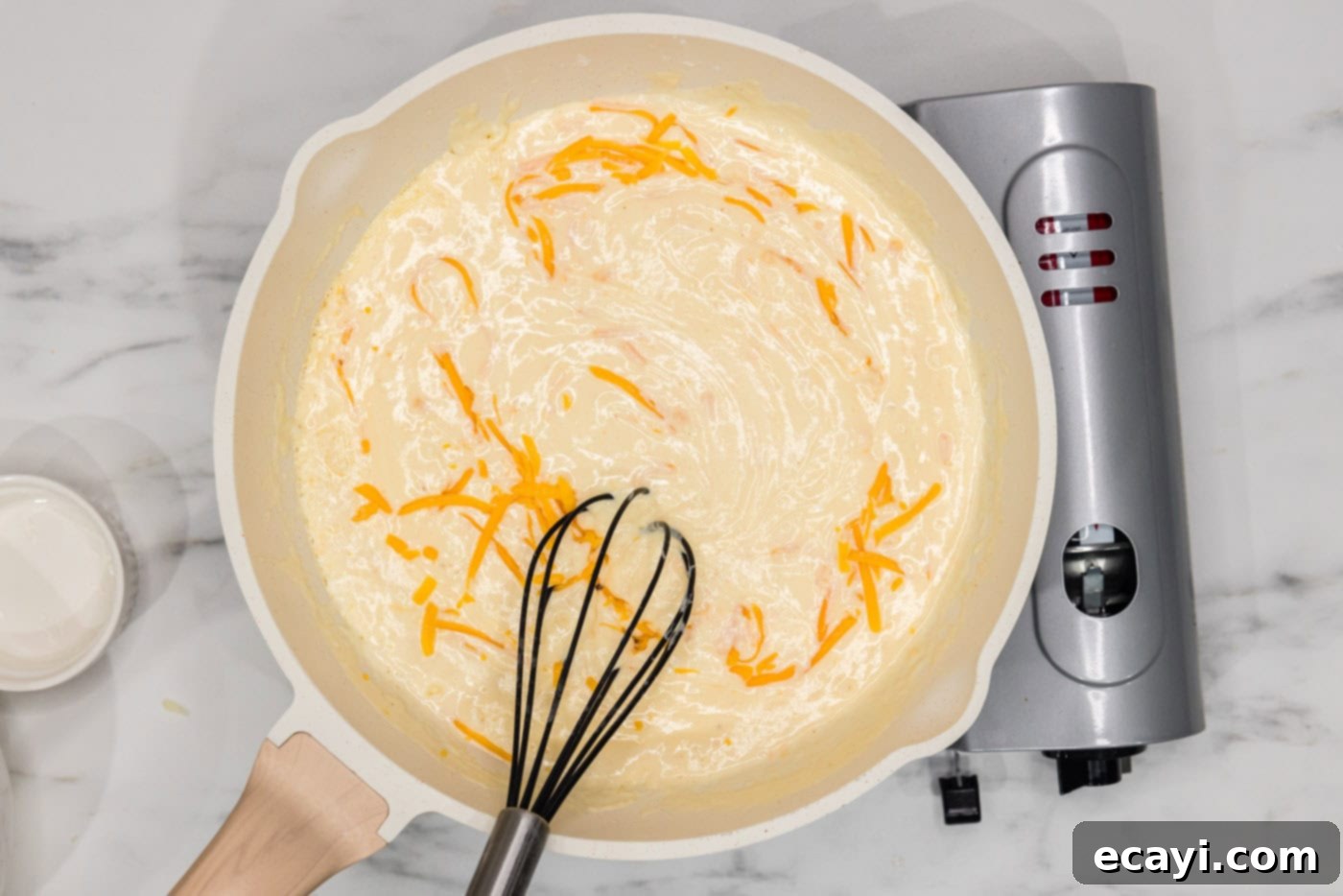 Buffalo Mac Bliss 8 whisking shredded cheese into béchamel in a skillet