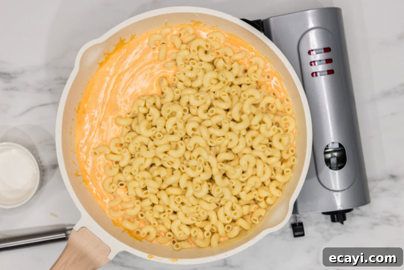 Buffalo Mac Bliss 10 elbow macaroni noodles added to buffalo cheese sauce in a skillet