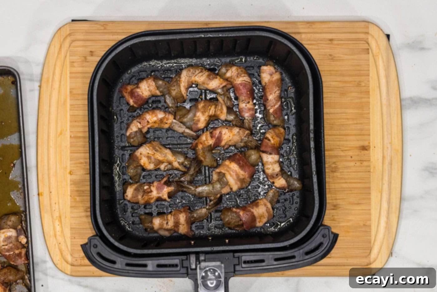 Crispy Air Fryer Bacon Wrapped Shrimp 11 bacon wrapped shrimp cooking in an air fryer basket, spaced evenly