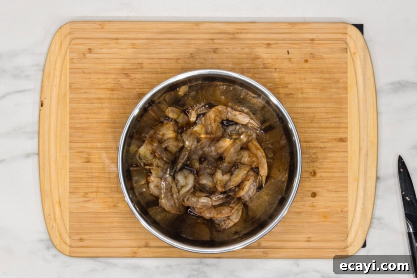 Crispy Air Fryer Bacon Wrapped Shrimp 6 shrimp marinating in a bowl with soy sauce and maple syrup glaze