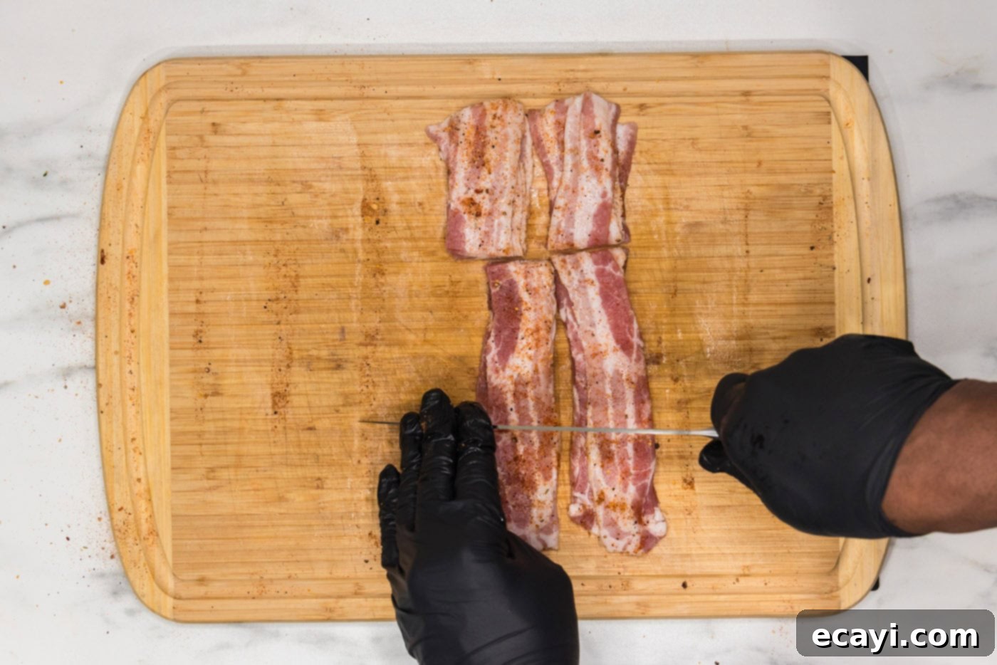 Crispy Air Fryer Bacon Wrapped Shrimp 7 slicing bacon into thirds on a cutting board for wrapping shrimp