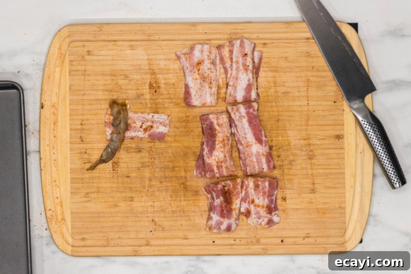 Crispy Air Fryer Bacon Wrapped Shrimp 8 wrapping shrimp in bacon on a cutting board, showing the technique