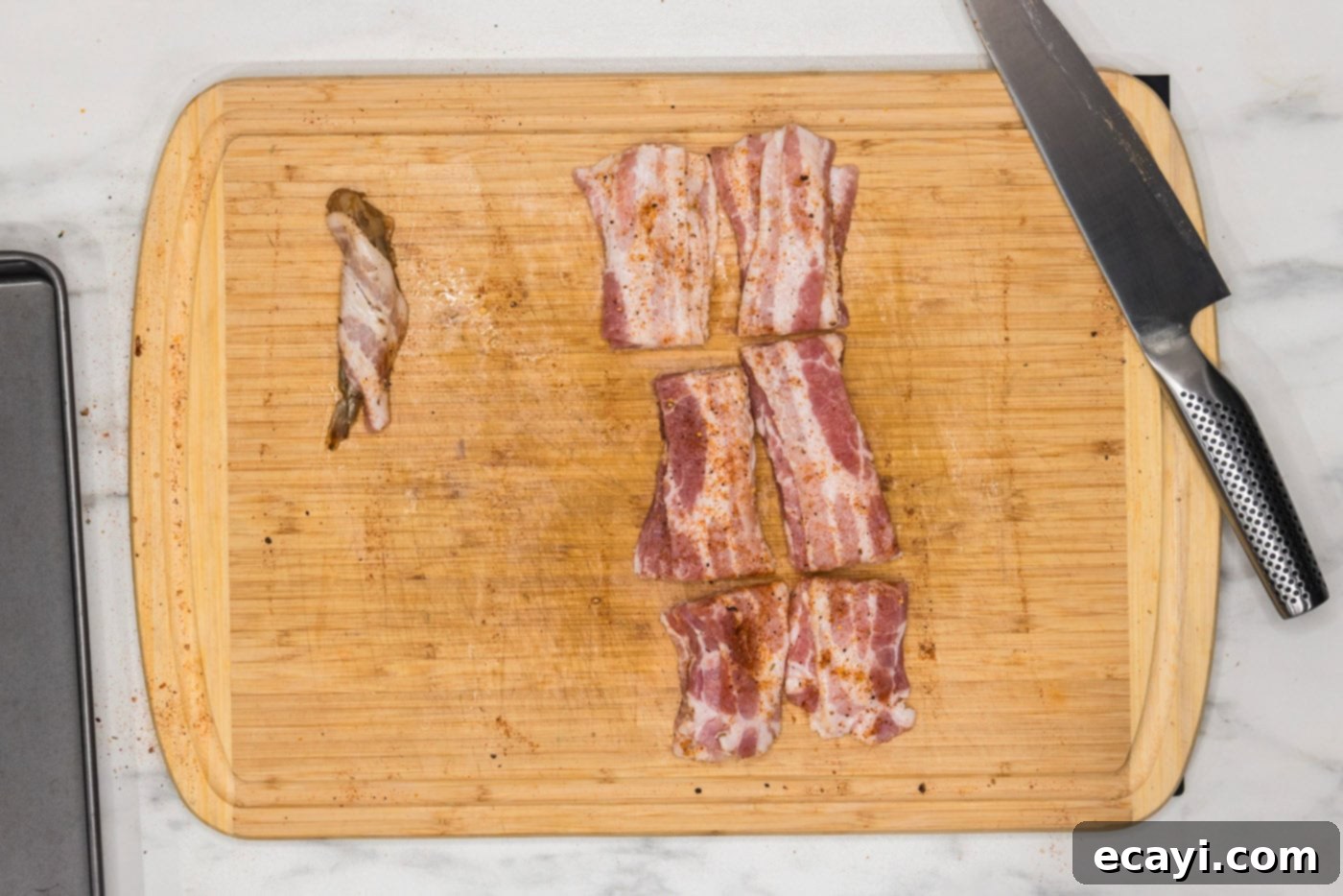 Crispy Air Fryer Bacon Wrapped Shrimp 9 bacon wrapped shrimp neatly arranged next to remaining bacon slices on a cutting board