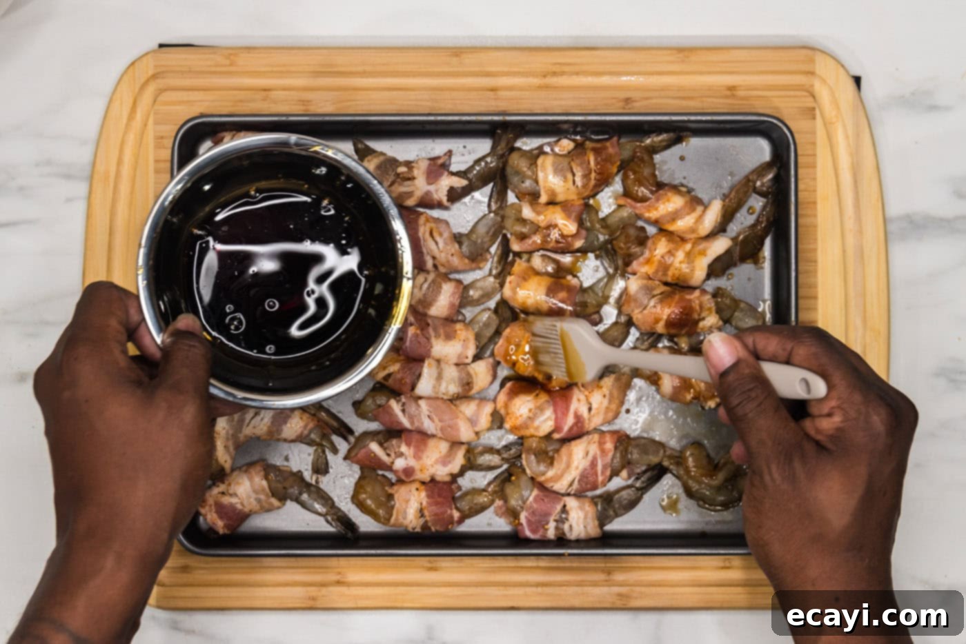 Crispy Air Fryer Bacon Wrapped Shrimp 10 pouring soy sauce mixture over bacon wrapped shrimp on a baking sheet before air frying