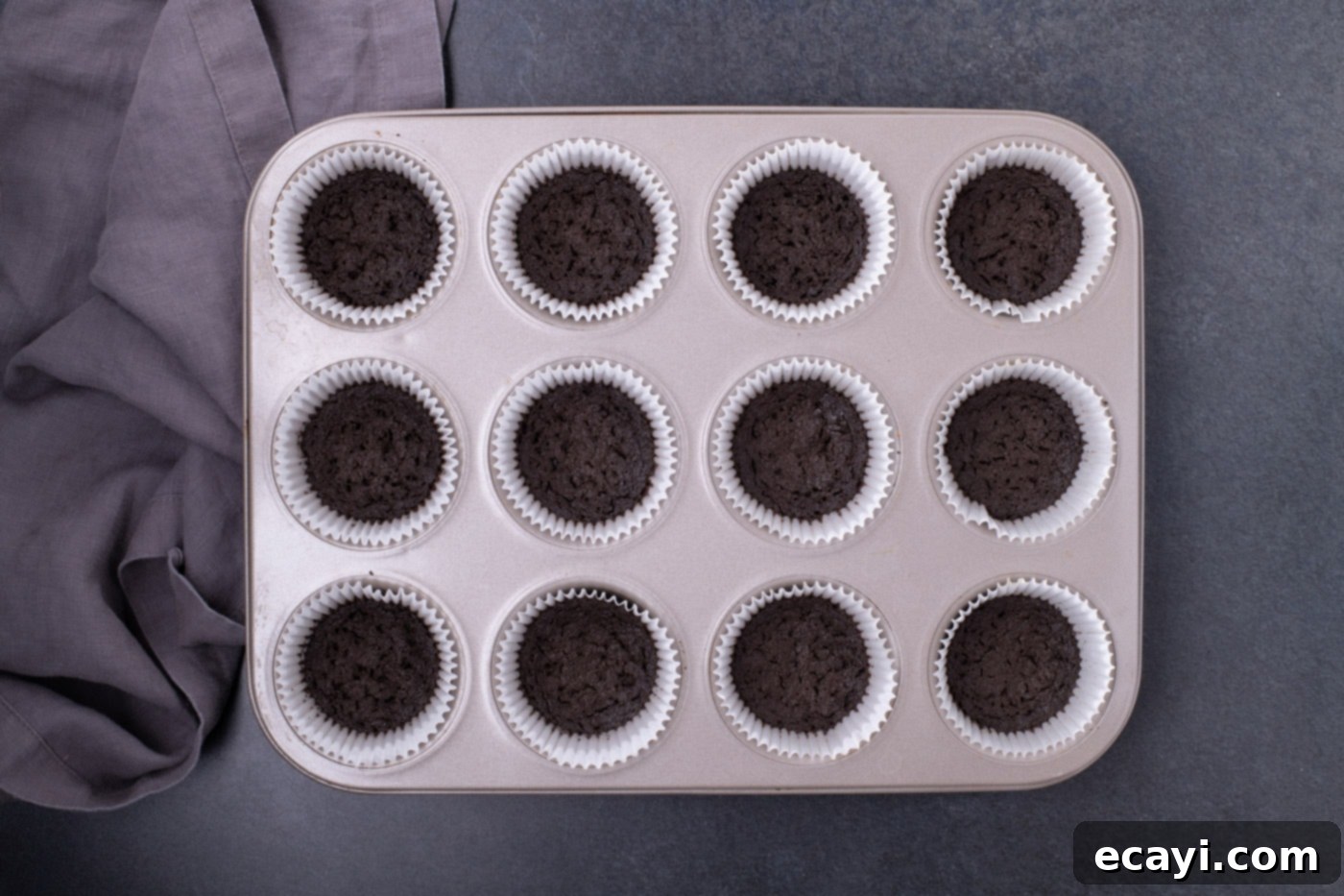 Festive Candy Corn Mini Cheesecakes 6 Baked Oreo cookie crusts sitting inside cupcake liners in a muffin pan, cooling down.
