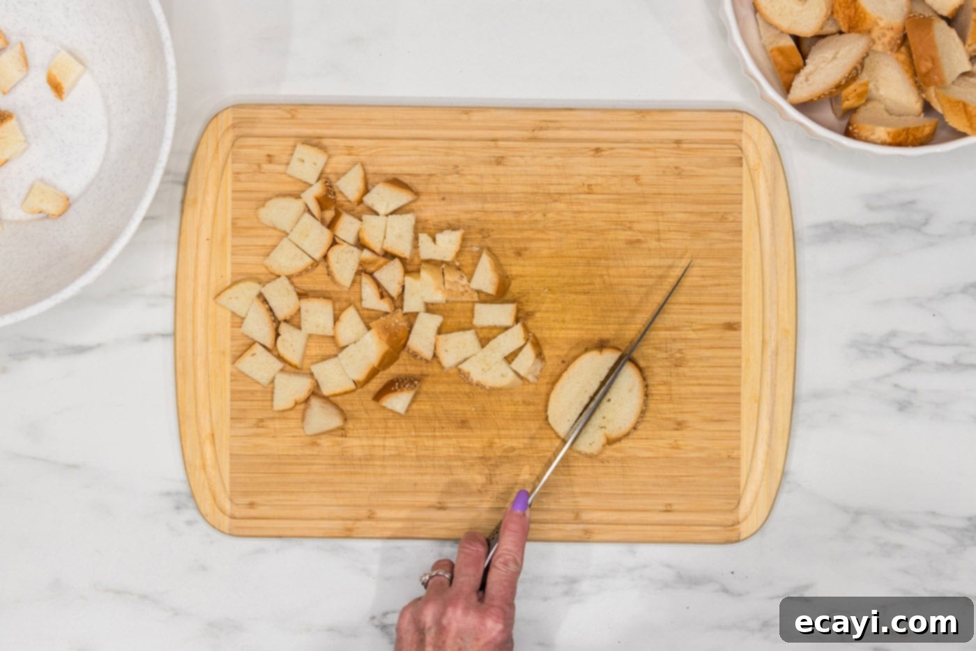 Crispy Golden Croutons 5 slicing breads into cubes on a cutting board