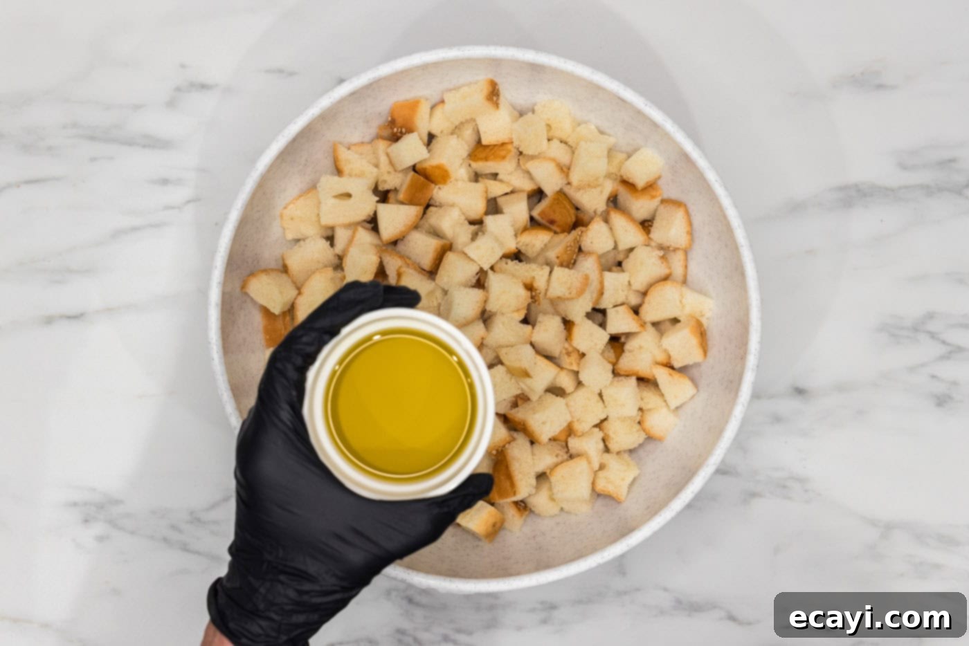 Crispy Golden Croutons 6 olive oil held over a bowl of cubed bread