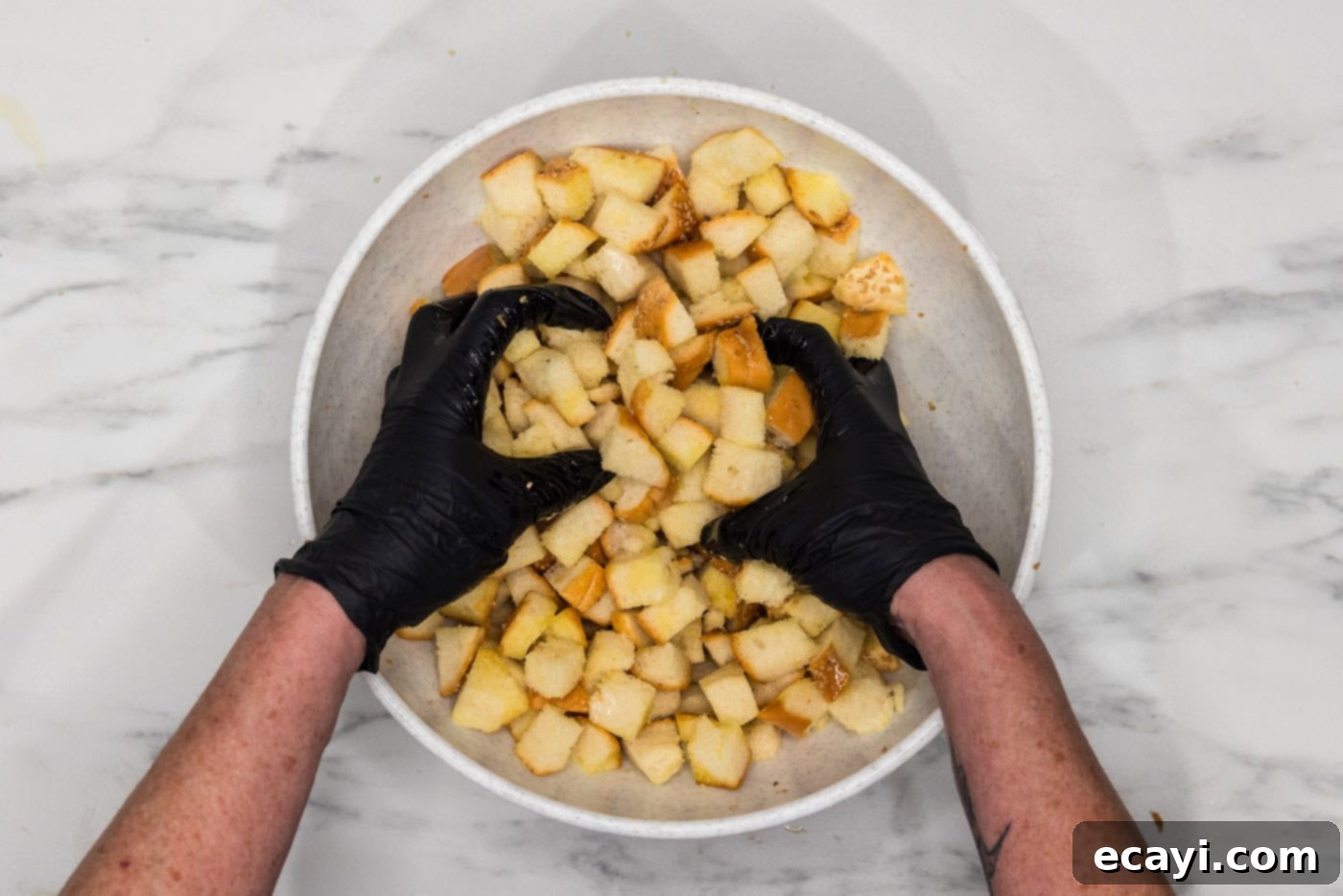 Crispy Golden Croutons 7 gloved hands mixing croutons with olive oil