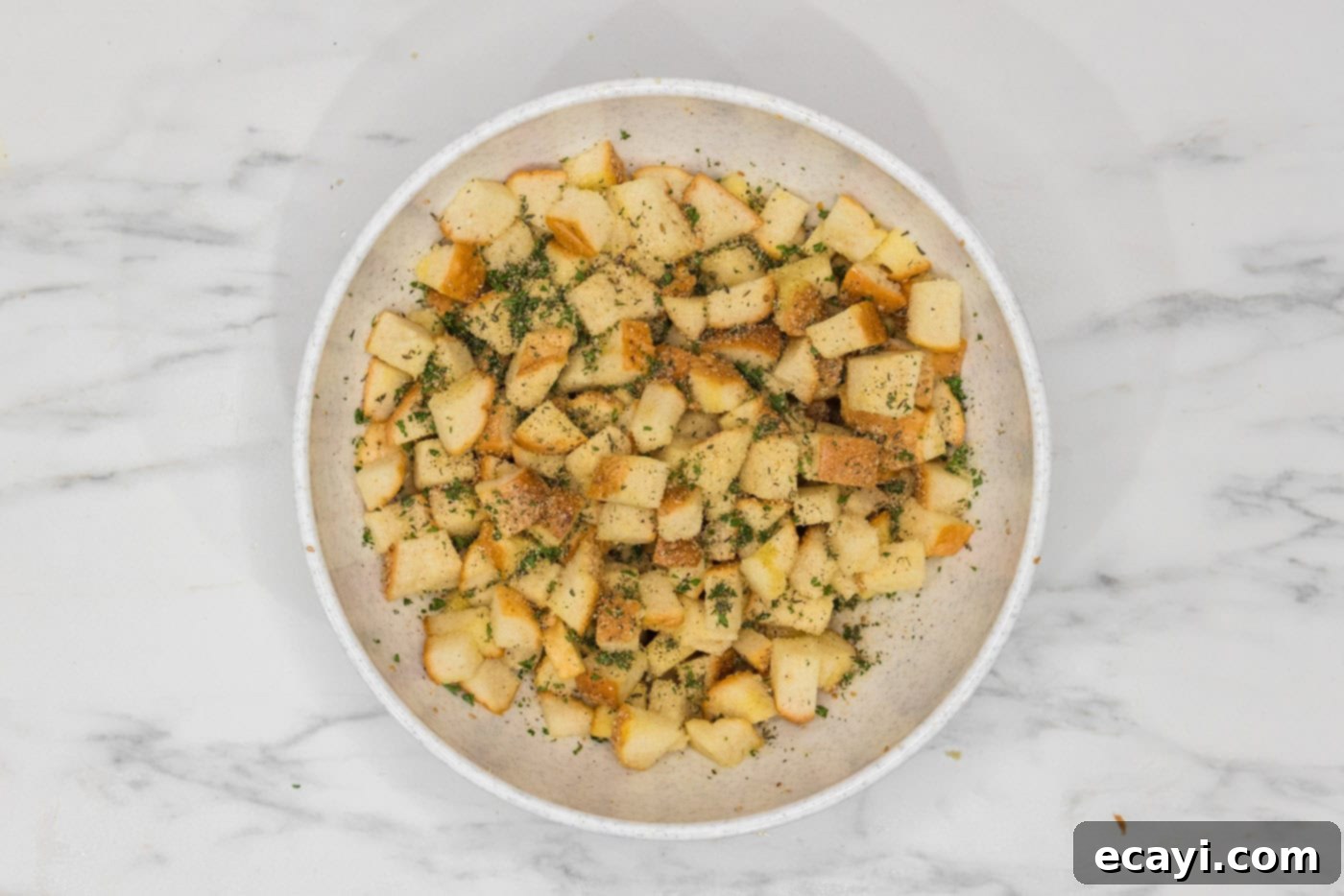 Crispy Golden Croutons 9 cubed bread with seasonings and herbs in a large bowl