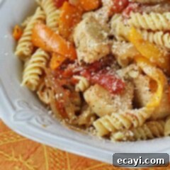 Savory Chicken and Pepper Pasta 19 A close up photo of chicken with peppers and pasta in a white bowl topped with Parmesan cheese.