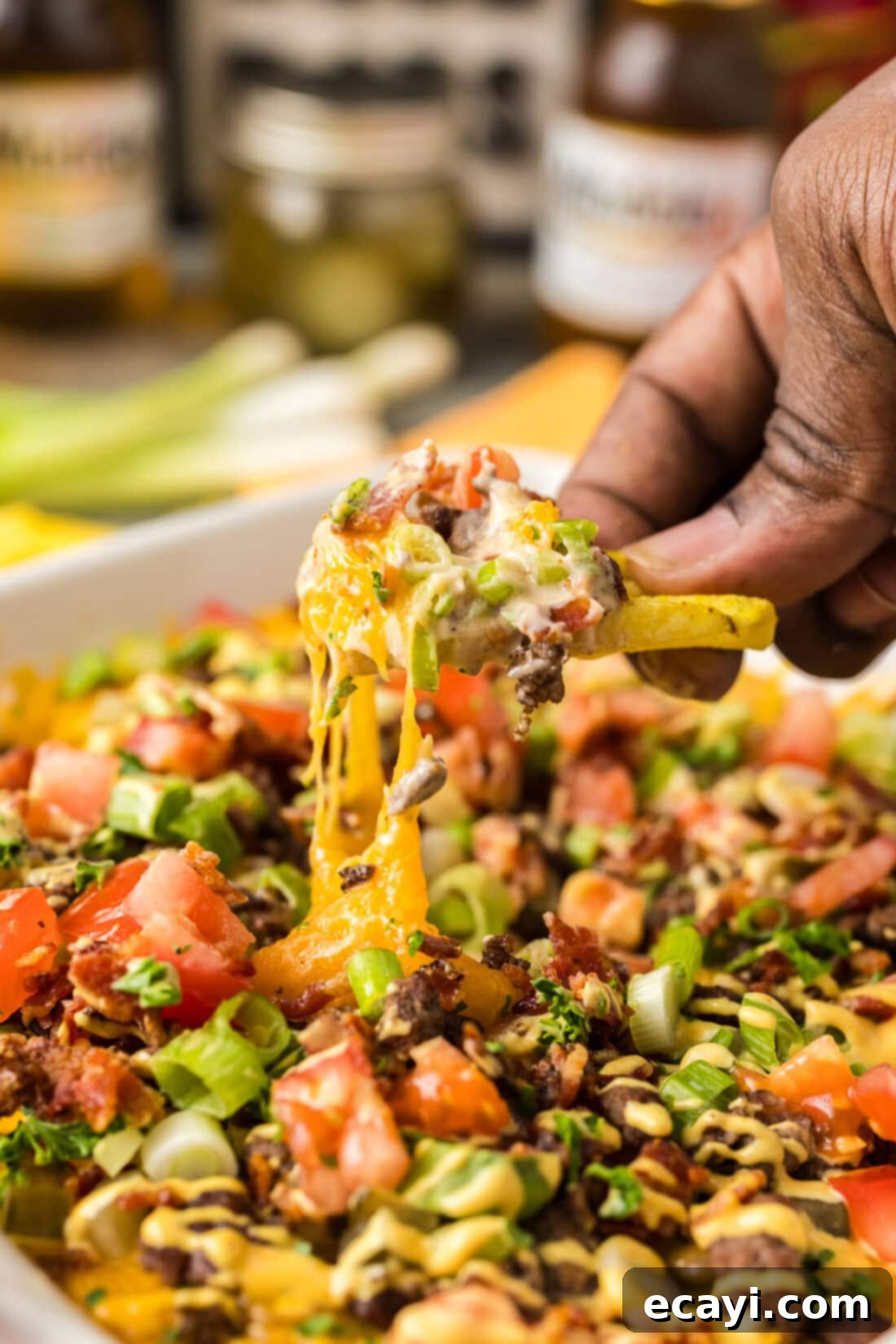 Loaded Cheeseburger Dip 2 Hand holding a chip full of Cheeseburger Dip