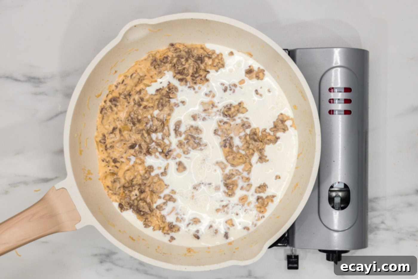Loaded Cheeseburger Dip 10 heavy cream added to cheesy beef mixture in a skillet