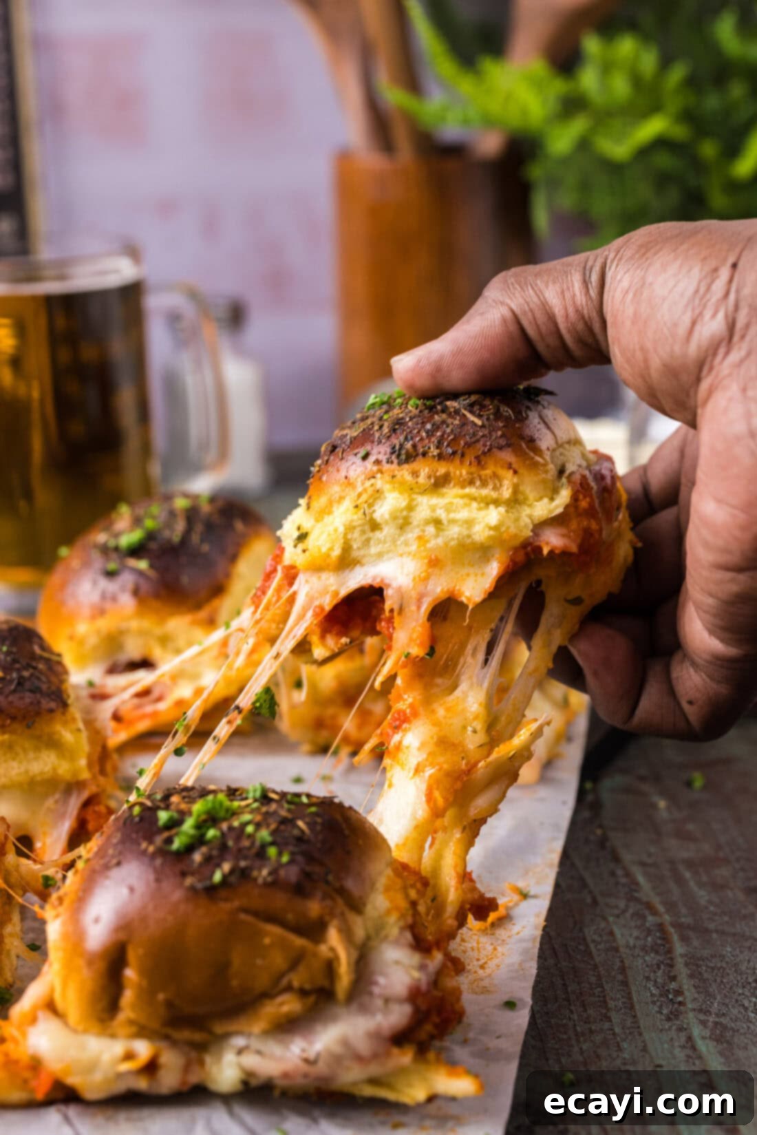 Cheesy Chicken Parmesan Sliders 2 Hand pulling up a Chicken Parmesan Slider, showcasing melted cheese and crispy chicken