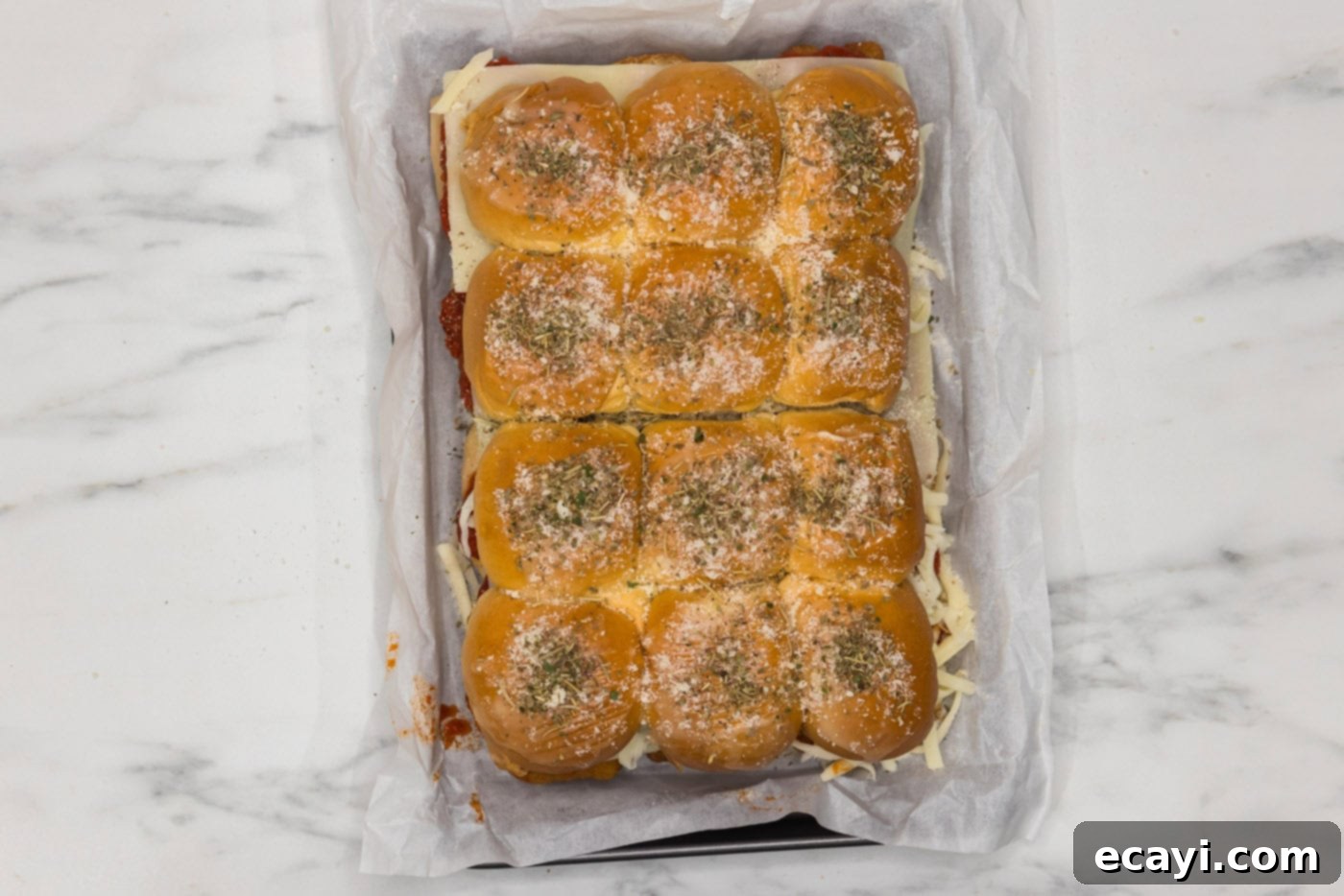 Cheesy Chicken Parmesan Sliders 11 Chicken parmesan sliders in a baking dish, garnished with grated parmesan cheese and Italian seasoning