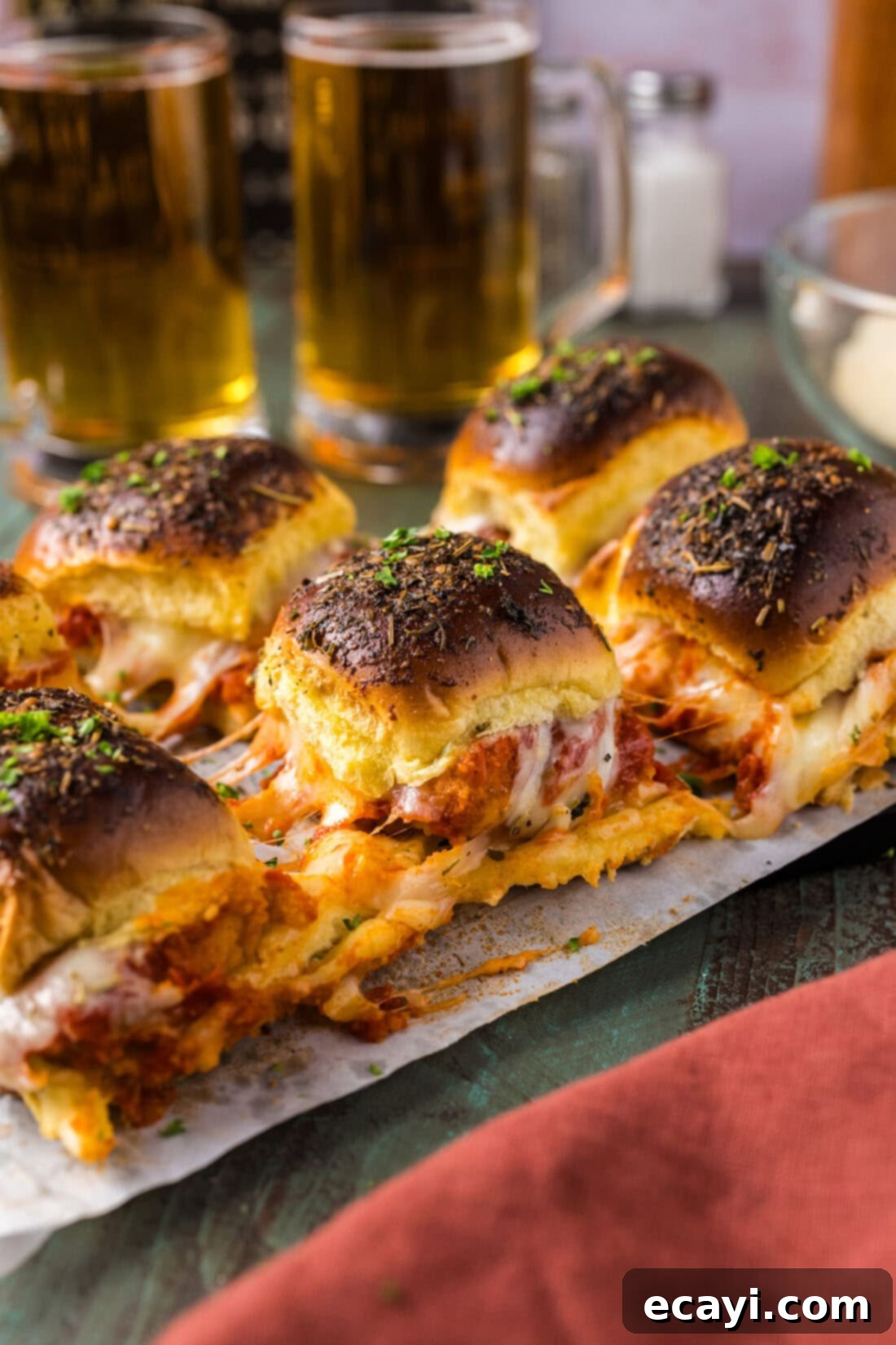 Cheesy Chicken Parmesan Sliders 3 Close up photo of Chicken Parmesan Sliders arranged neatly on parchment paper in a baking dish
